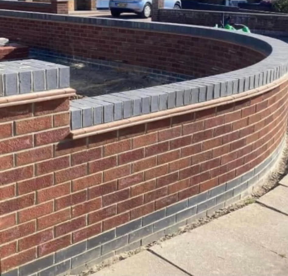 Curved red brick garden wall with contrasting grey coping by LM Building Services