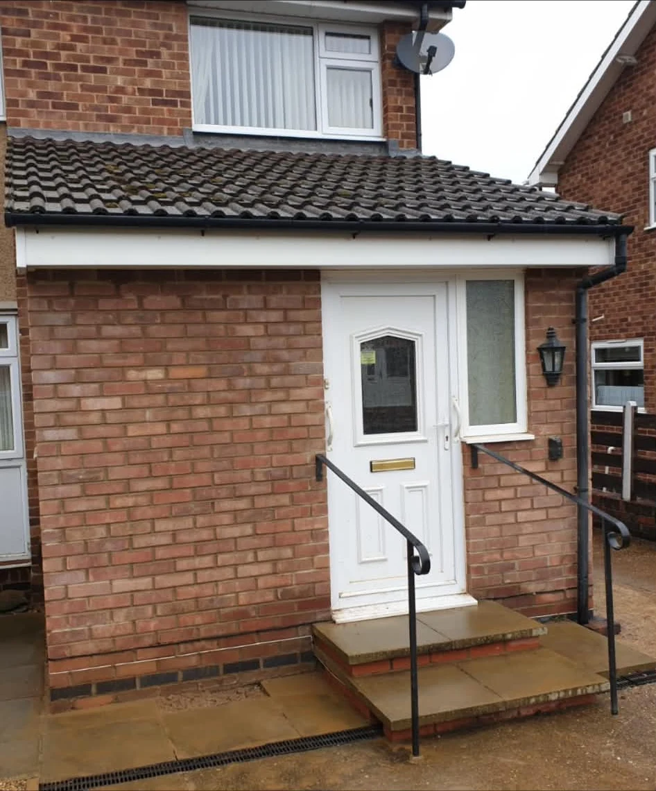 Brick home extension with front door and tiled roof